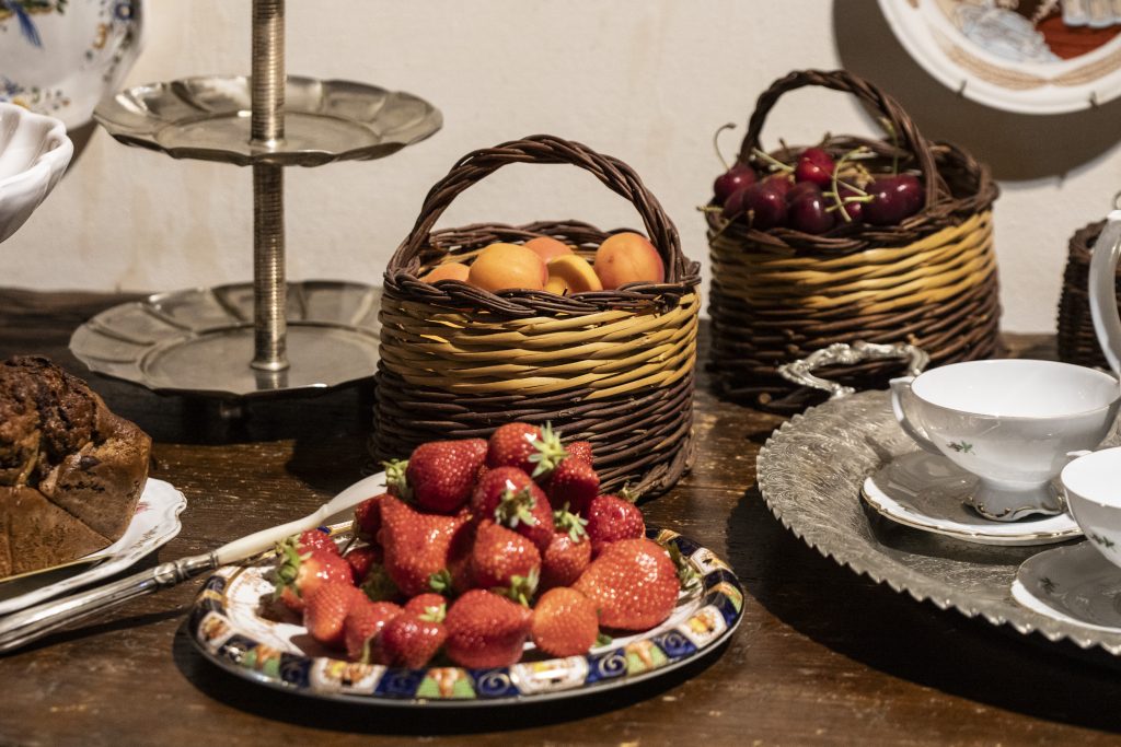 Table at L'Aurora, Borgo dei Cipressi, laid with fresh fruit, cake and vintage china