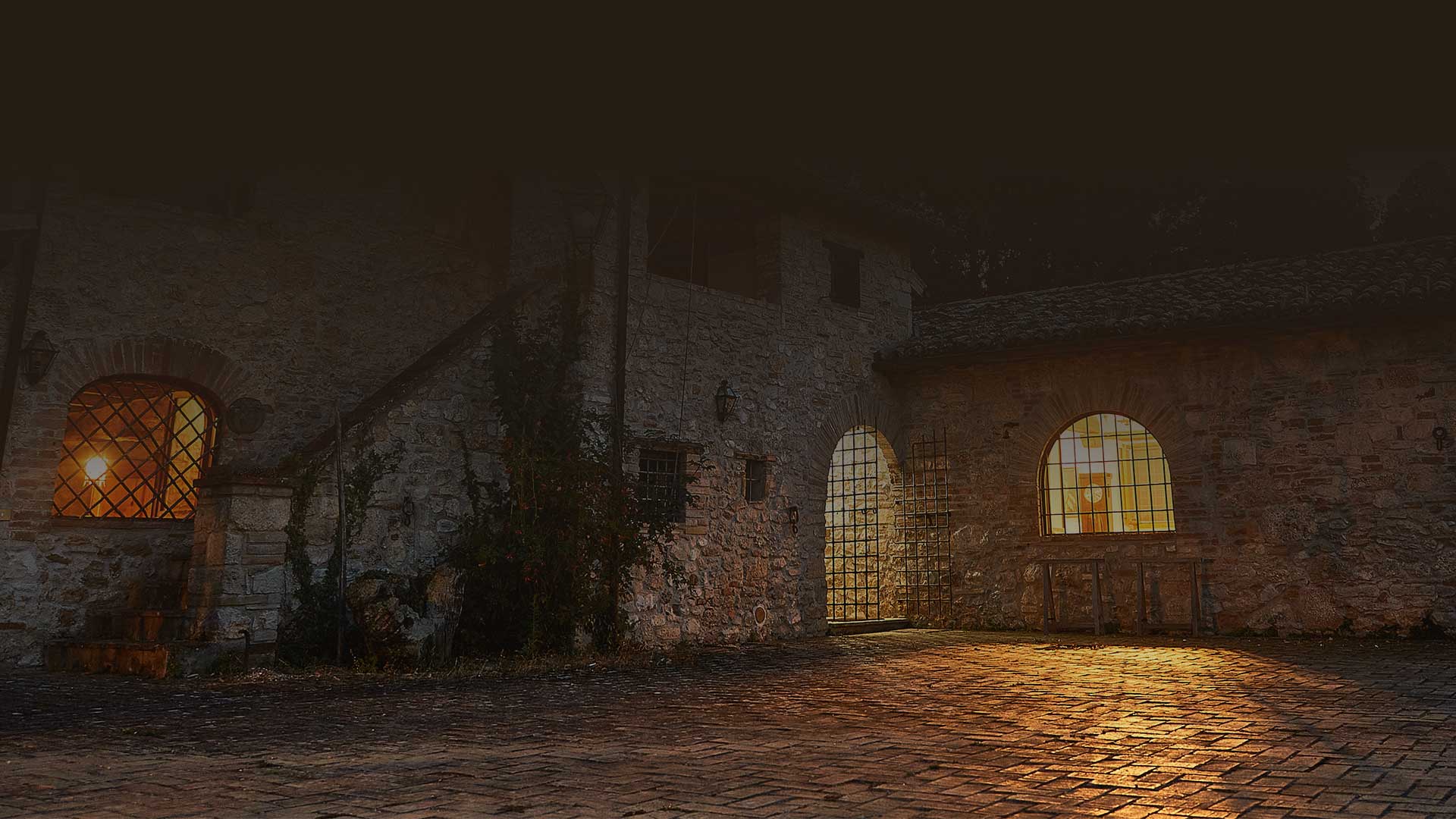 Lamplit stone courtyard of Casale Alessandri in the evening