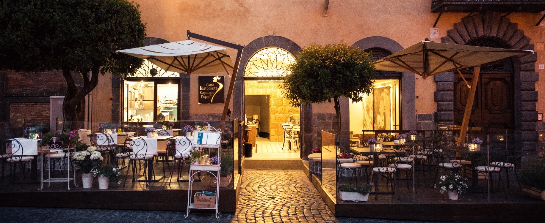 Capitano del Popolo terrace in Orvieto, lit at dusk with parasols and outdoor tables