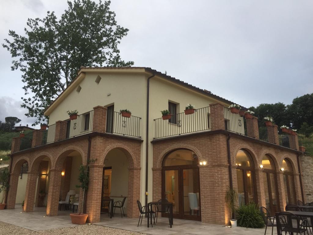 Exterior of John's Restaurant near Todi, with arched brick loggia and terrace tables at dusk