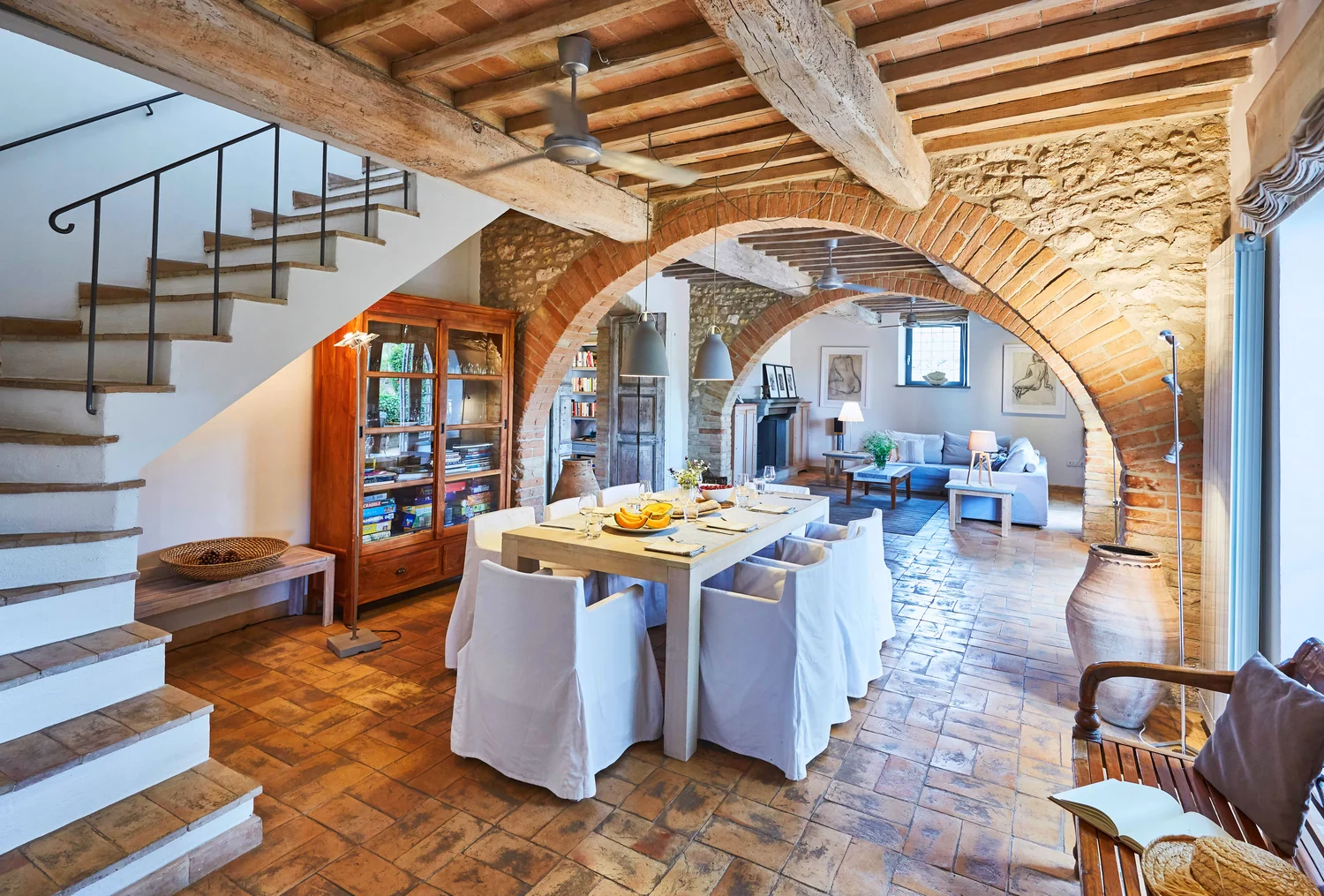 Indoor dining table beneath a brick archway with terracotta floors