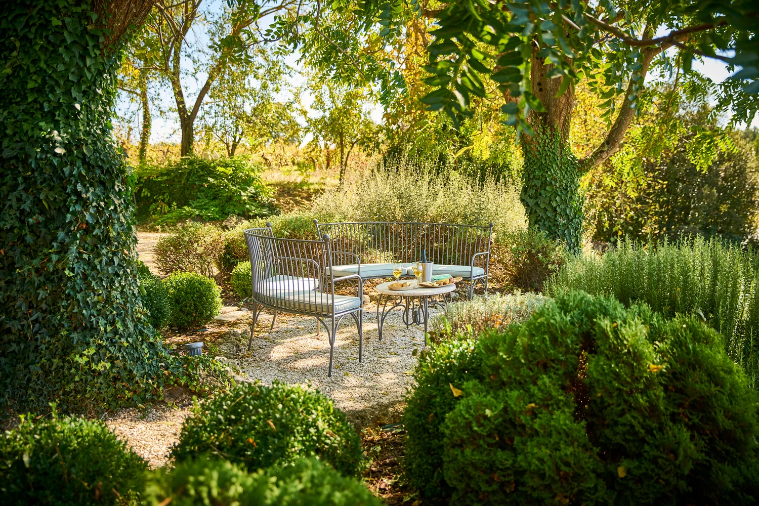 Shaded garden seating area surrounded by hedges and trees