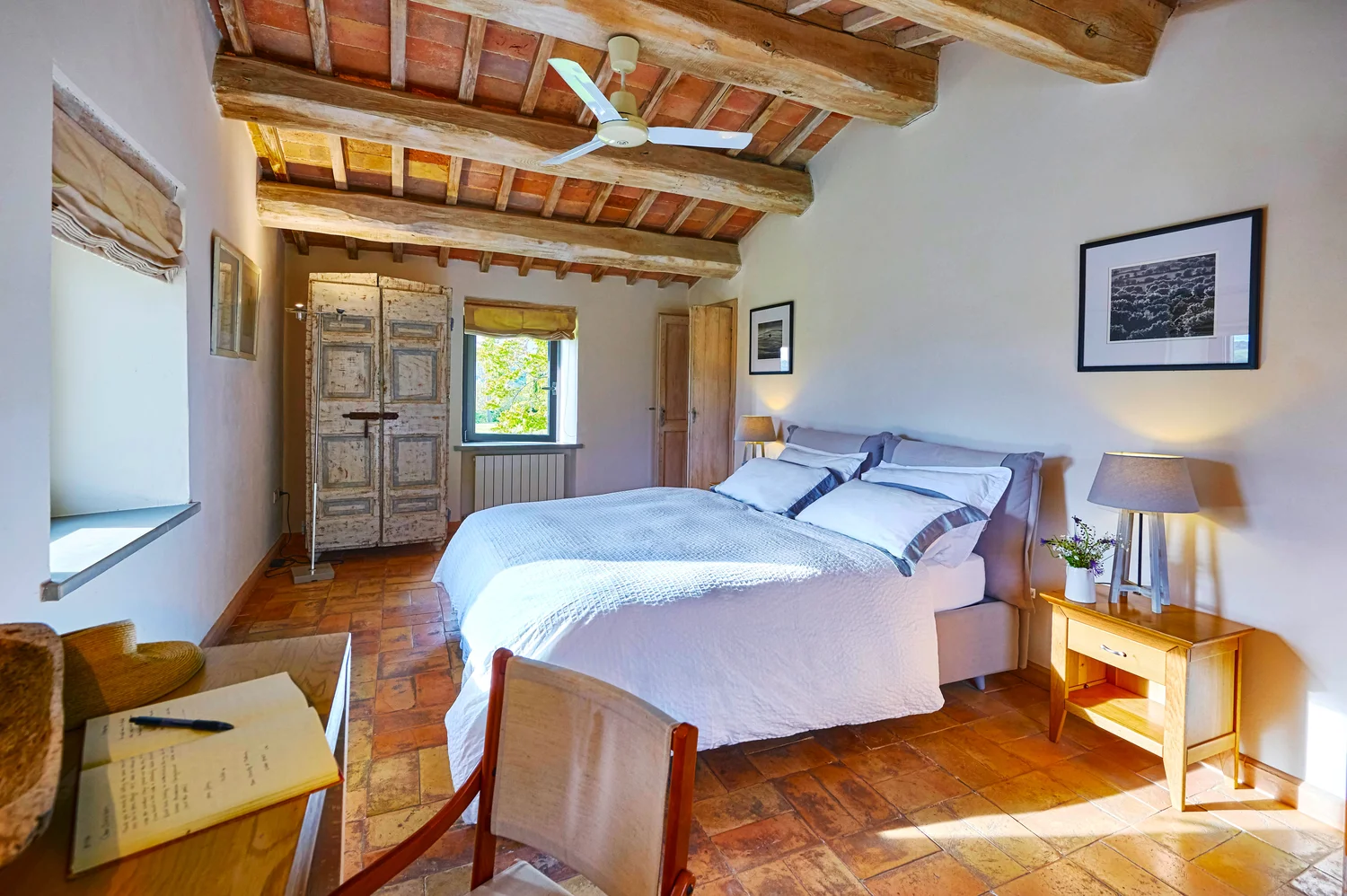 Triple aspect master bedroom with beamed ceiling and terracotta floor
